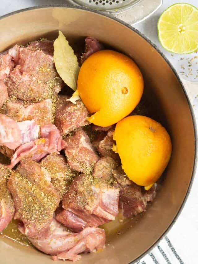 carnitas pork, oranges, bay leaves, cumin in a le creuset with lime juicer.