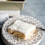 piece of banana sheet cake on a black and white plate with a fork.