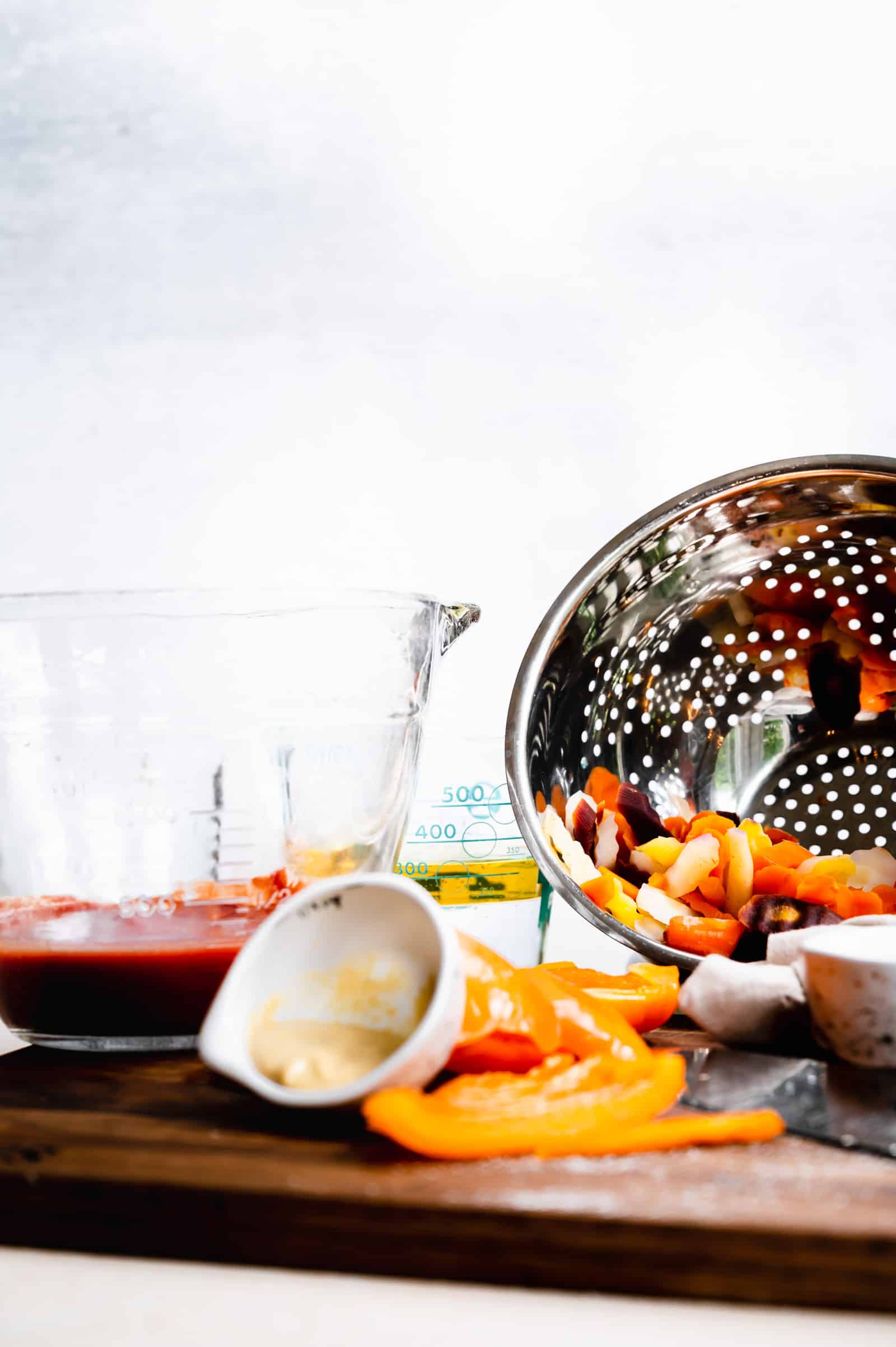 salad dressing ingredients and cooked carrots in a colander.