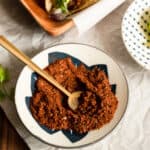 white and blue bowl filled with spices and a small gold spoon.