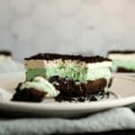 a bite out of a mint chocolate chip ice cream cake on a white plate.