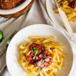 two bowls of pasta with tomato sauce and bowl of meatballs and cheese.