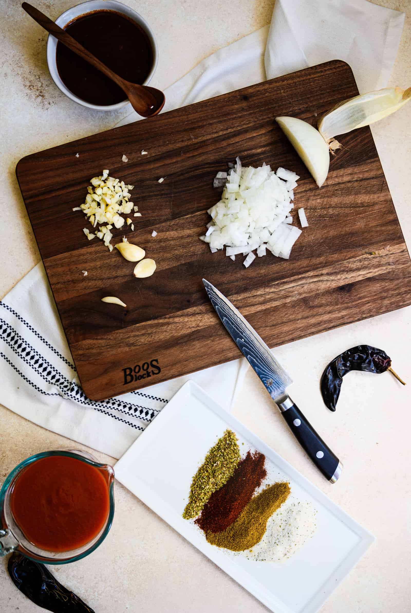 wooden board with a chopped onion, garlic and spices and bowls tomato sauces.