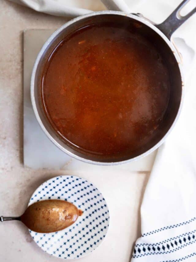 adobo sauce in a sauce pan with a spoon on a small dish.