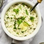overheard shot of white rice with cilantro and lime and a spoon with a wooden handle.