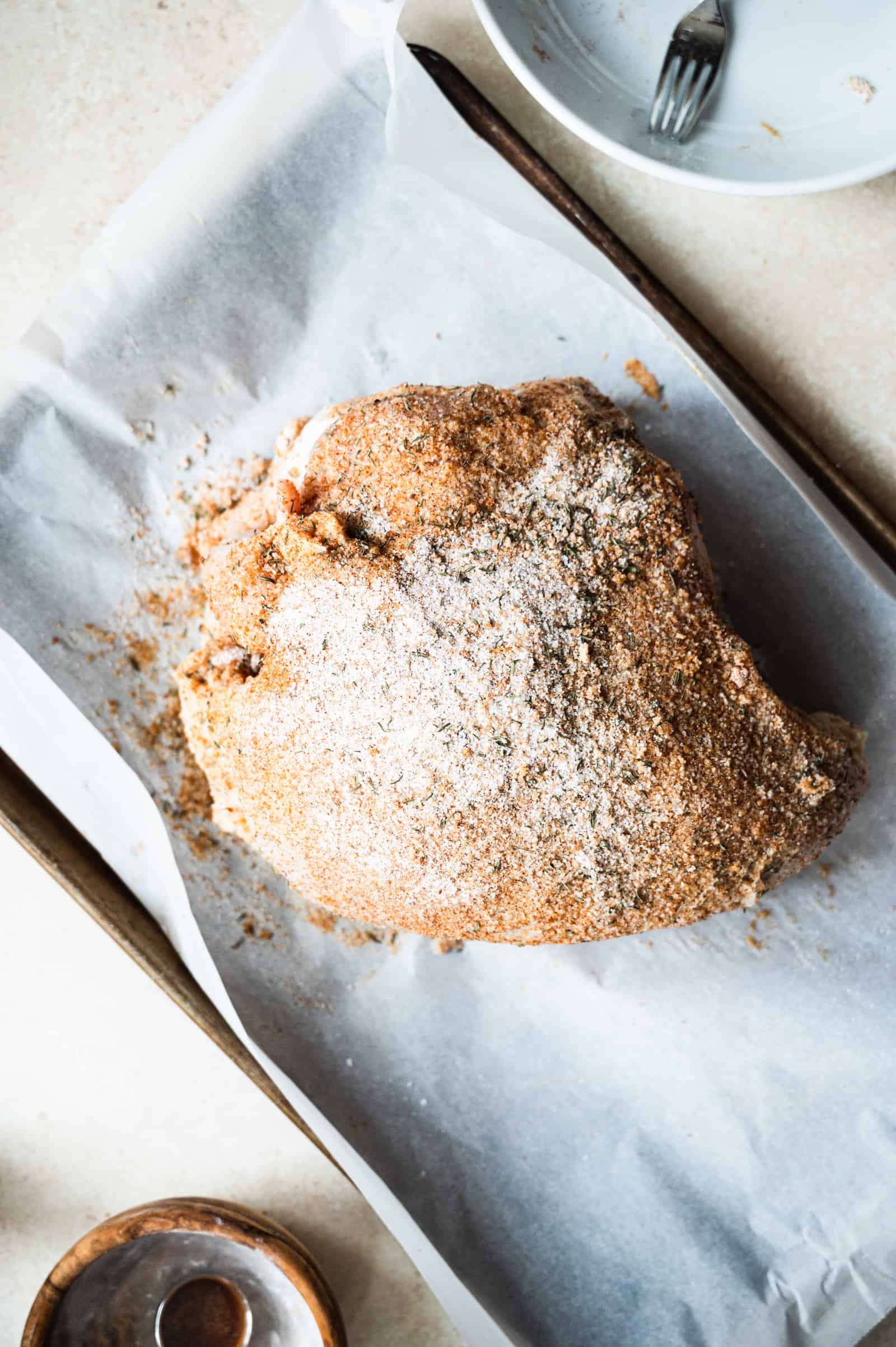 whole turkey breast with a dry brine on it on a sheet pan.
