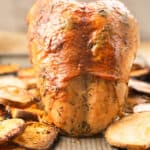 cooked whole turkey breast on a sheet pan with roasted potatoes.