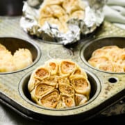 whole heads of roasted garlic in a muffin tin.