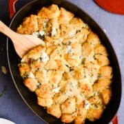 red gratin pan with baked biscuits pieces covered in cheddar and blue cheese