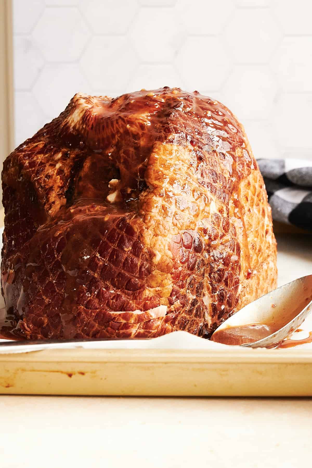 front view of a spiral ham on a sheet pan with a spoon.