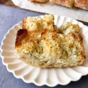 baked garlic bread on a white scalloped plate.