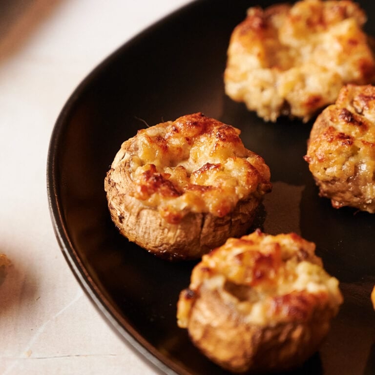 four stuffed mushrooms on a black plate.