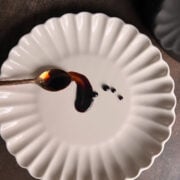 White ruffled plate smeared with a copper spoon and balsamic glaze.
