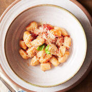 bowl of homemade gnocchi with red sauce on a brown background