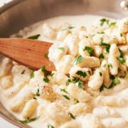skillet of cream sauce with gnocchi sprinkled with fresh parsley