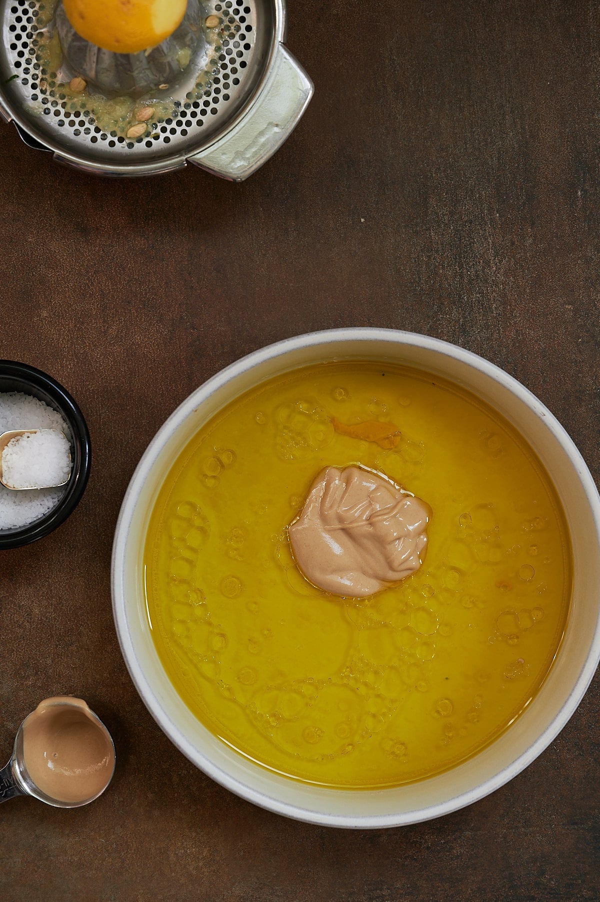 overhead shot of oil and mustard for salad dressing on dark background.