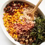 white serving dish of cooked farro with chopped dates, pancetta dressing and kale