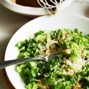 white bowl of salad greens dressed with balsamic vinaigrette