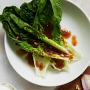 white bowl with fresh romaine leaves drizzled with fig balsamic dressing.