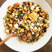 white bowl with finished roasted veggie panzanella and lemon vinaigrette dressing nearby