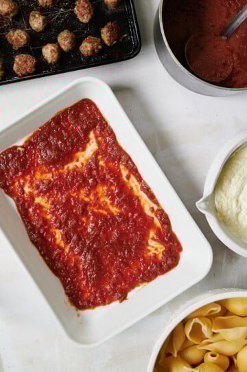 white baking dish with red sauce and meatballs, sauce and jumbo shells