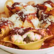 close up of meatball stuffed shells in a white round baking dish