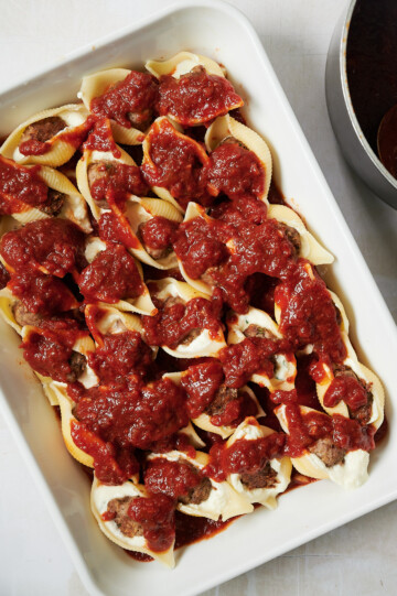 white baking dish filled with stuffed meatball shells with ricotta and topped with red sauce
