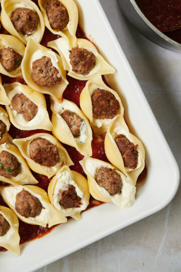 white baking dish of stuffed shells with meatballs and ricotta