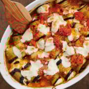 baked eggplant rollatini in white baking dish with wooden spatula