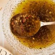 glass bowl with spoon holding olive oil bread dip with garlic and herbs