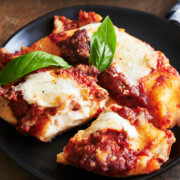 Close up of two baked ricotta cheese manicotti topped with meat sauce