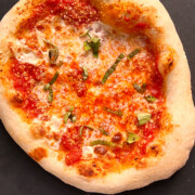 Whole Neapolitan pizza on a black pizza peel.