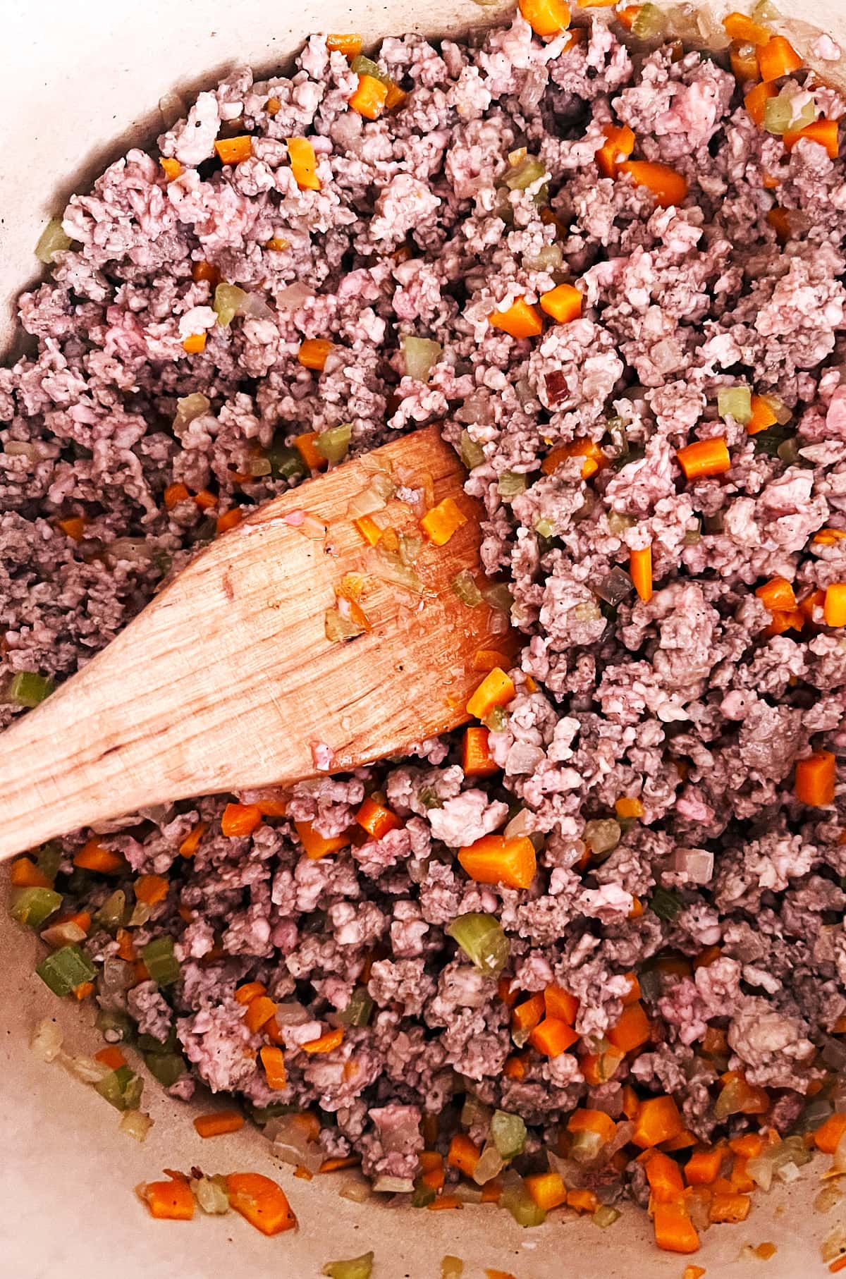 paddle spatula browning meat, carrots, celery and onion for bolognese sauce