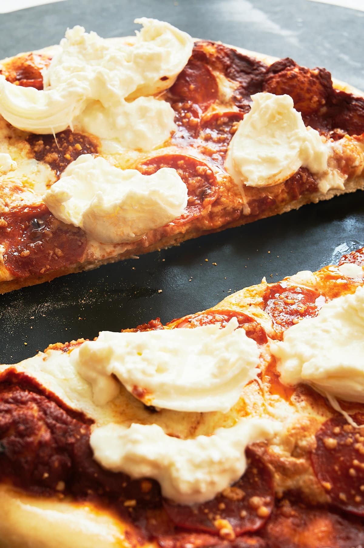 two halves of vodka sauce and pepperoni pizza with burrata.