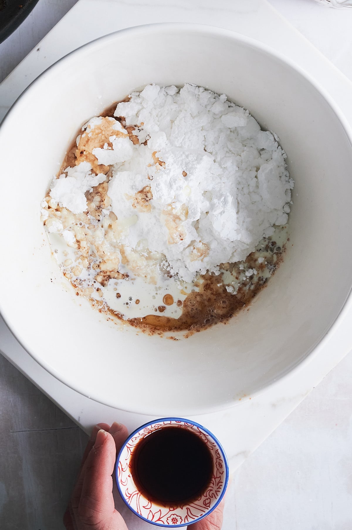 adding ingredients for apple cake glaze to a white mixing bowl