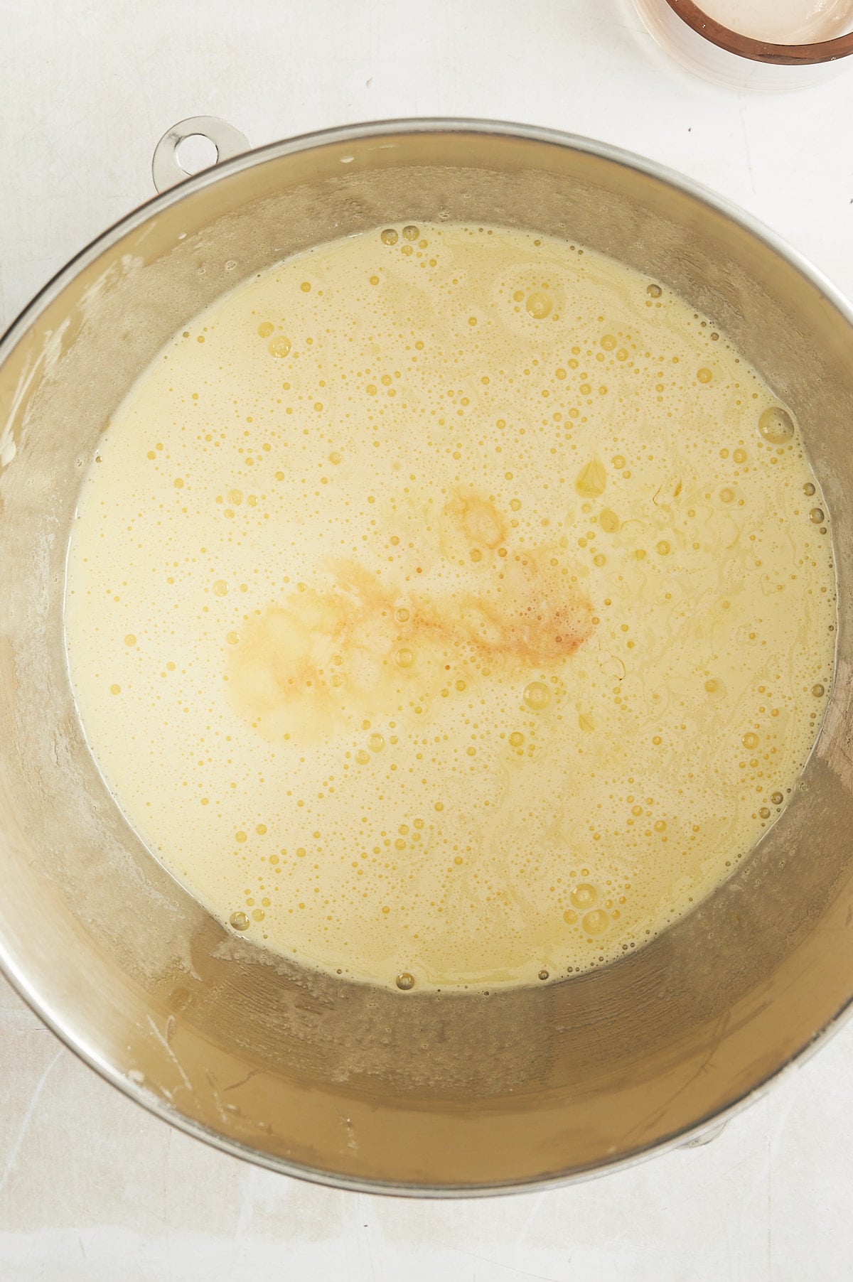 Mixing bowl of apple cake batter with oj and vanilla