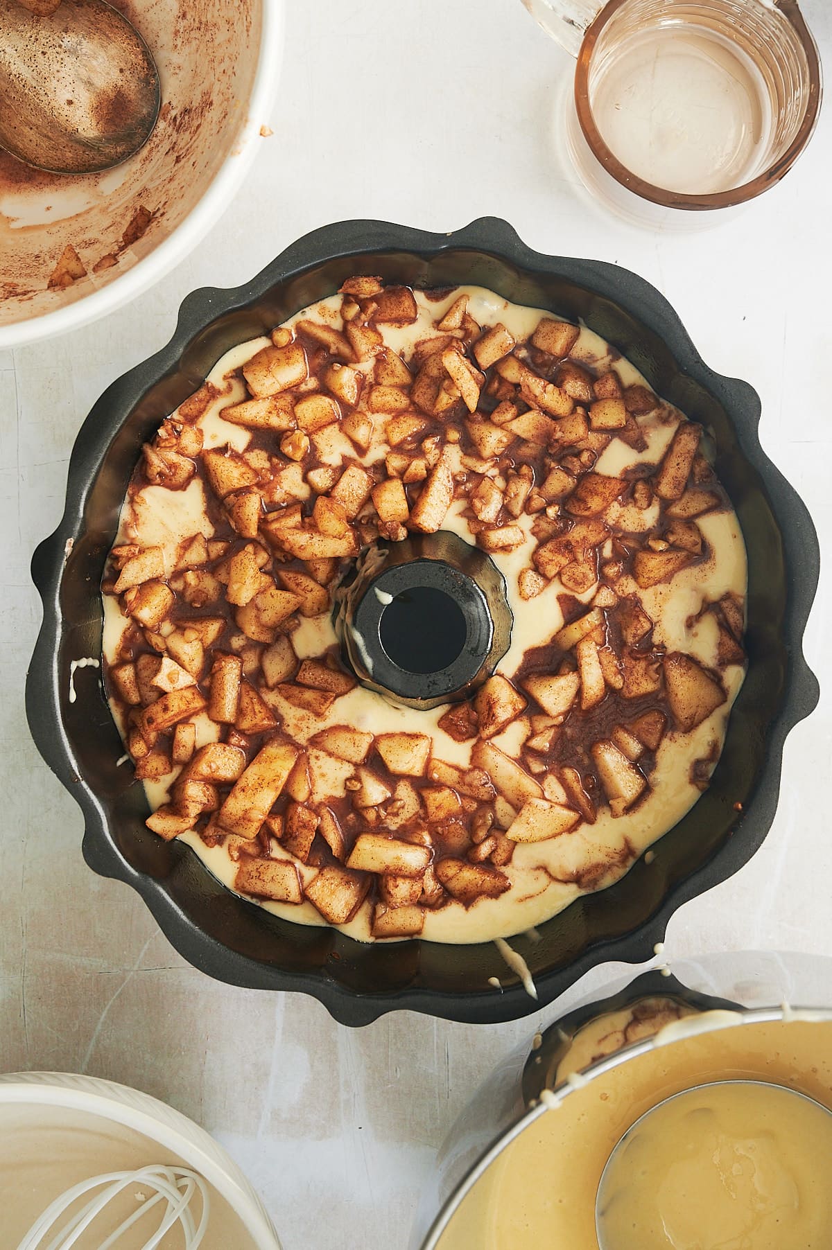Black bundt pan of layers of apple bundt cake