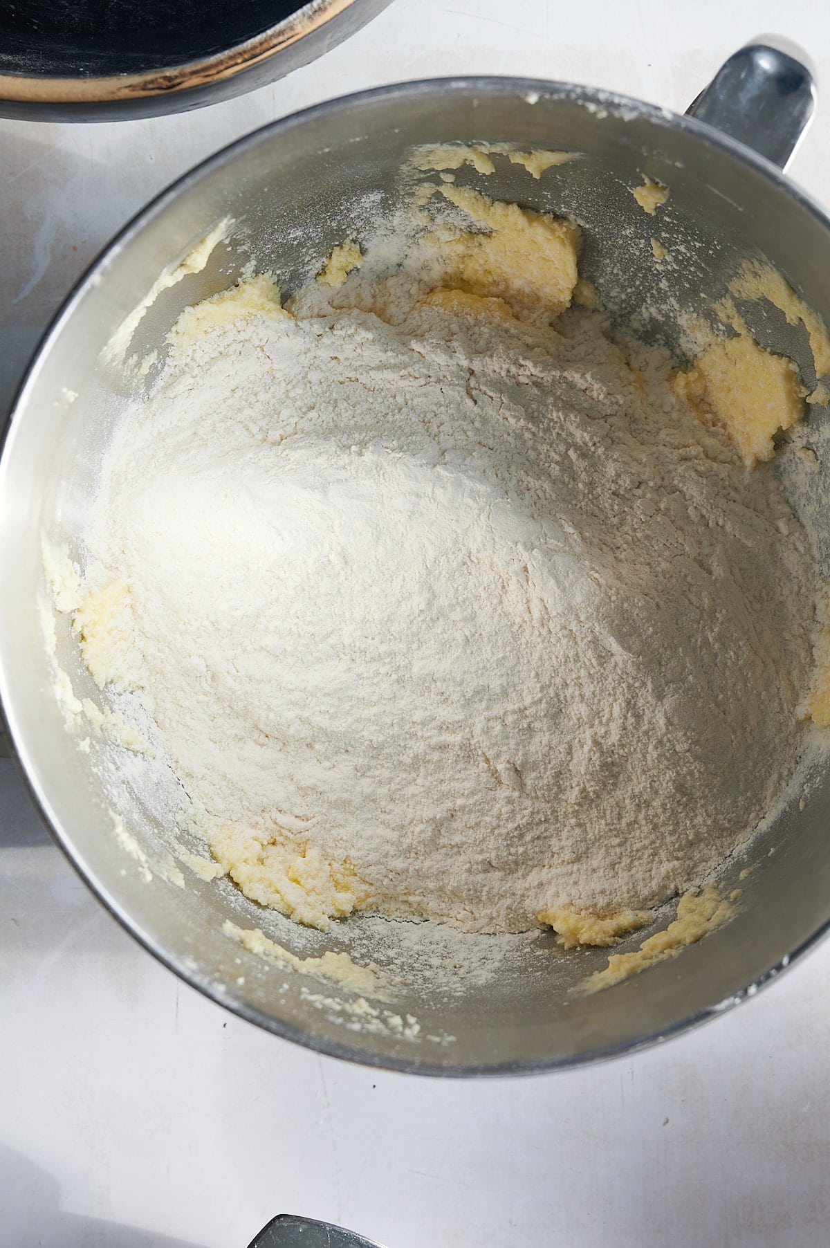 flour ingredients being added to lemon knot cookie dough in mixer bowl.