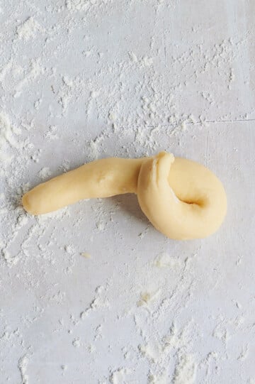 step 2 of rolling lemon knot dough on white floured background.