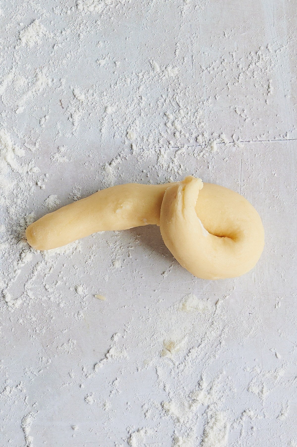 step 2 of rolling lemon knot dough on white floured background.
