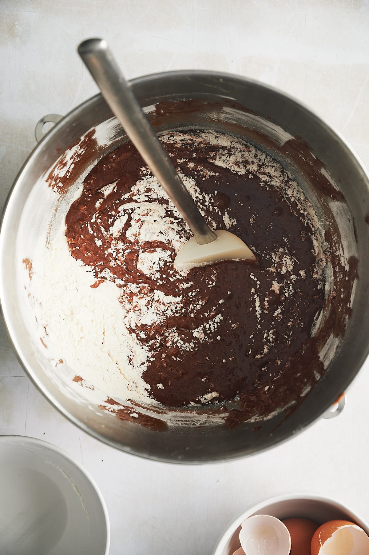 mixing bowl of brownie batter with flour being stirred in.