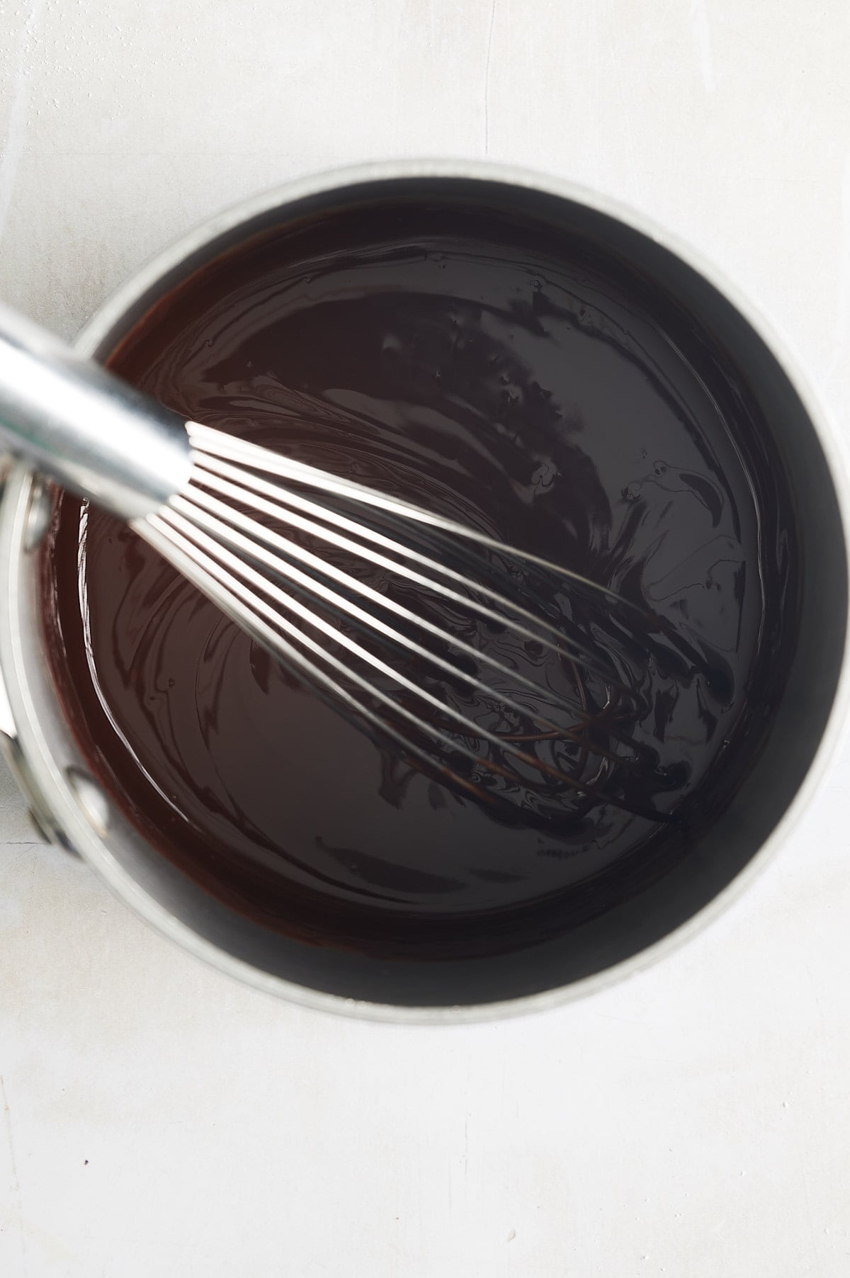 saucepan of chocolate ganache being whisked.