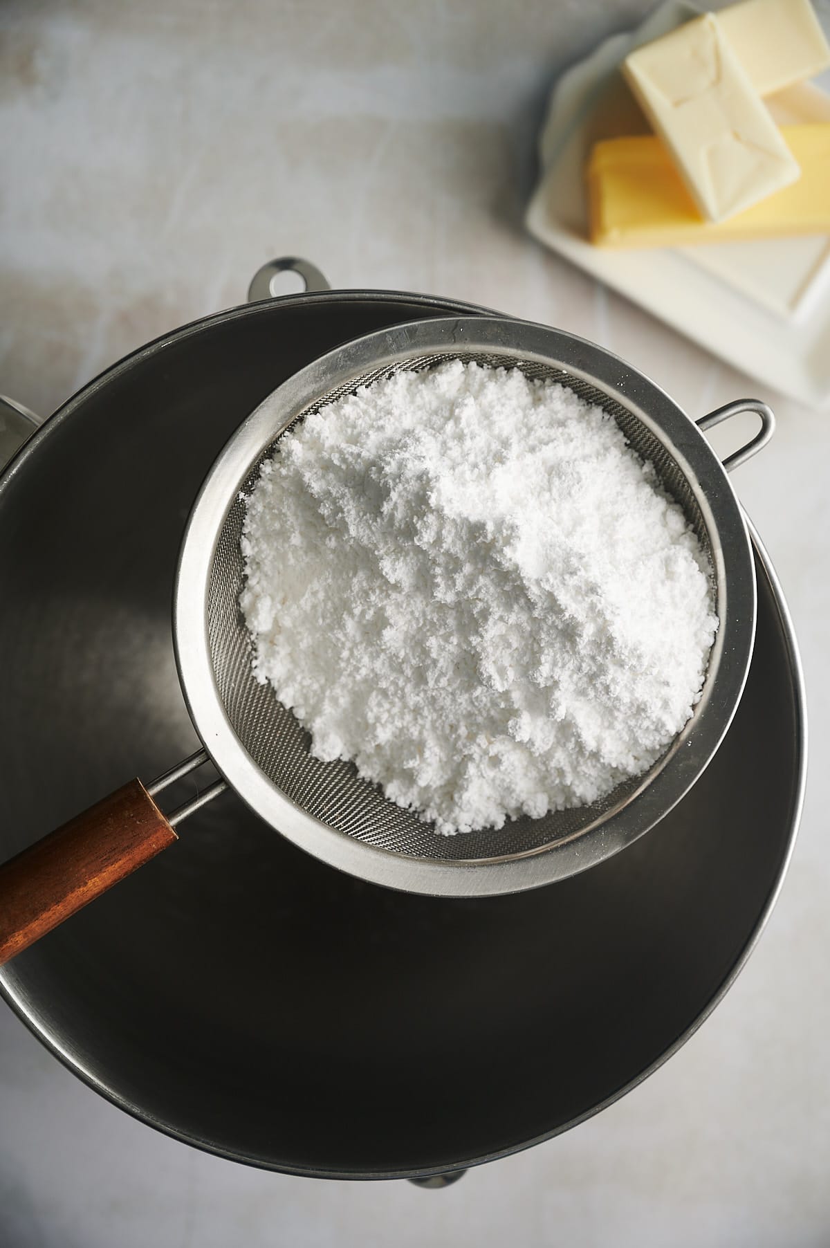 confectioners sugar in strainer over bowl.