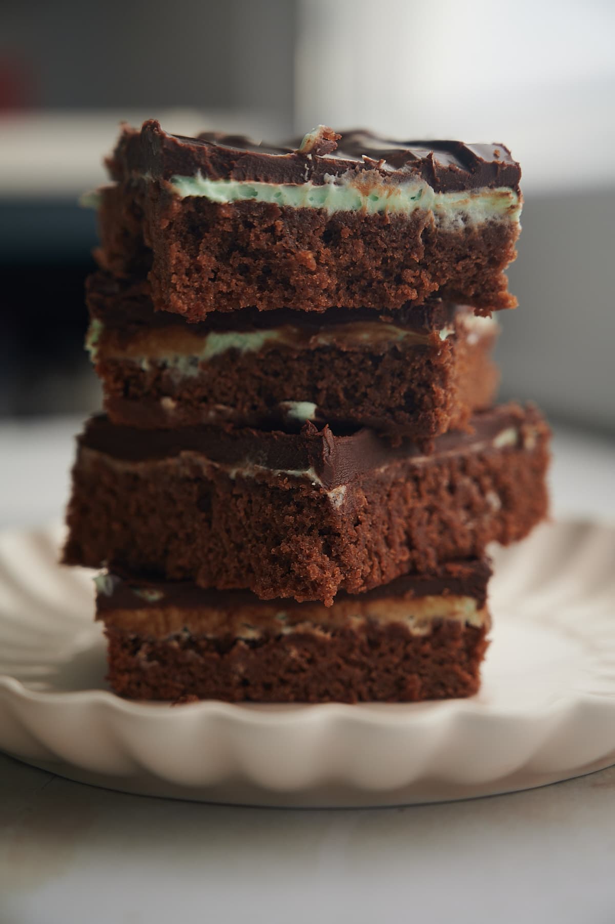 stack of mint chocolate brownies on a ruffled white plate.