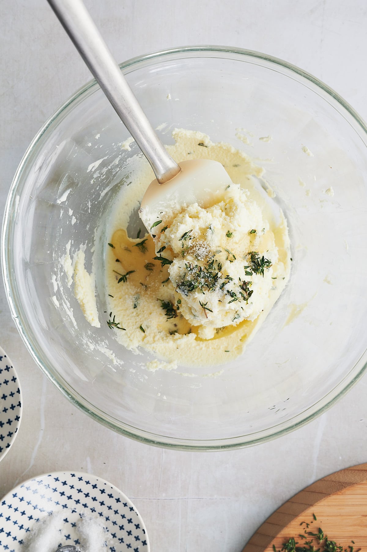 mascarpone cheese dip being mixed by a stainless spatula with fresh thyme leaves, salt and honey.