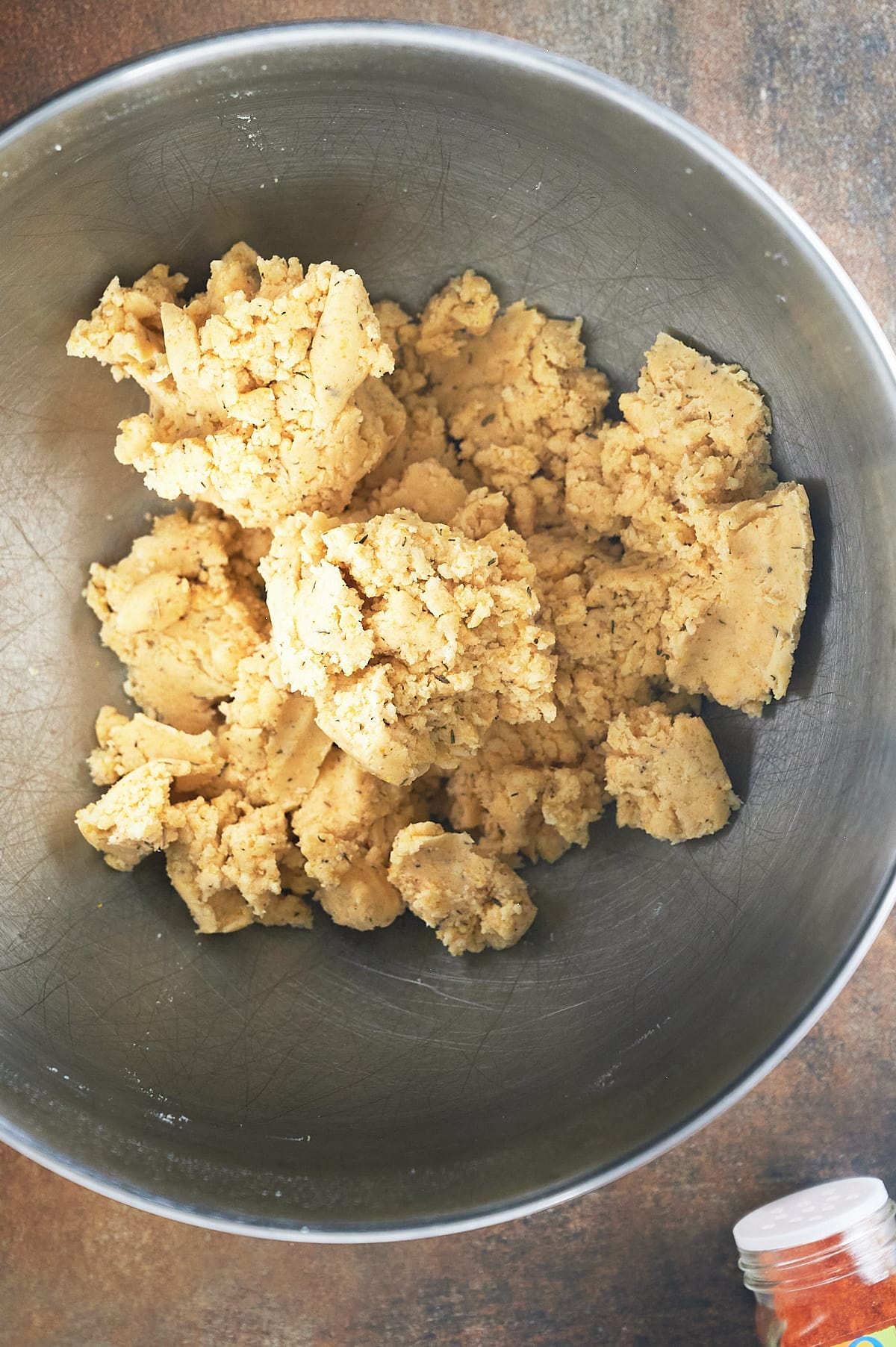 cayenne pepper mixed into parmesan thyme cracker dough in mixing bowl.