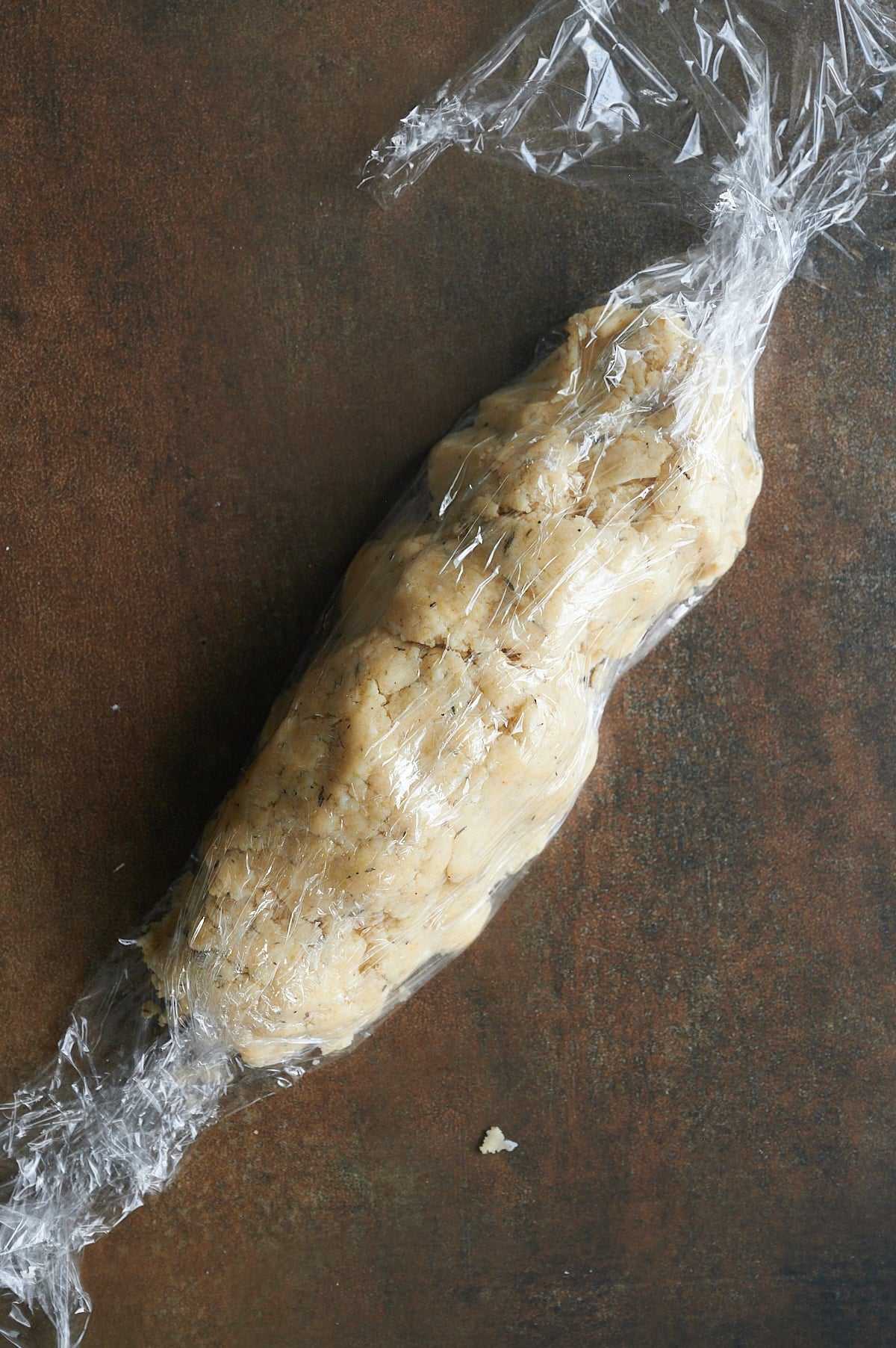 parmesan thyme cracker dough being wrapped in plastic.