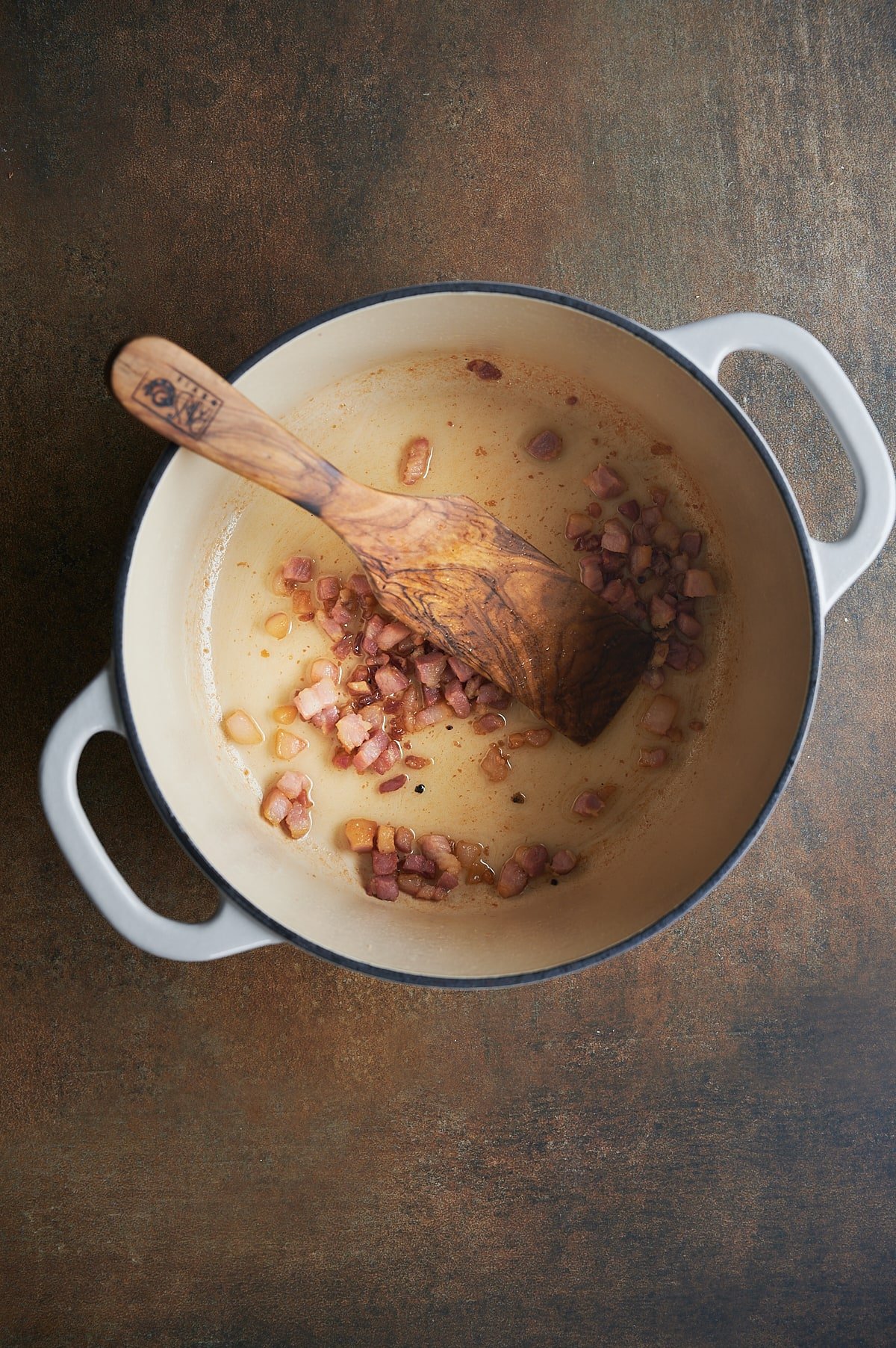 White pan of browned pancetta for white Bolognese sauce