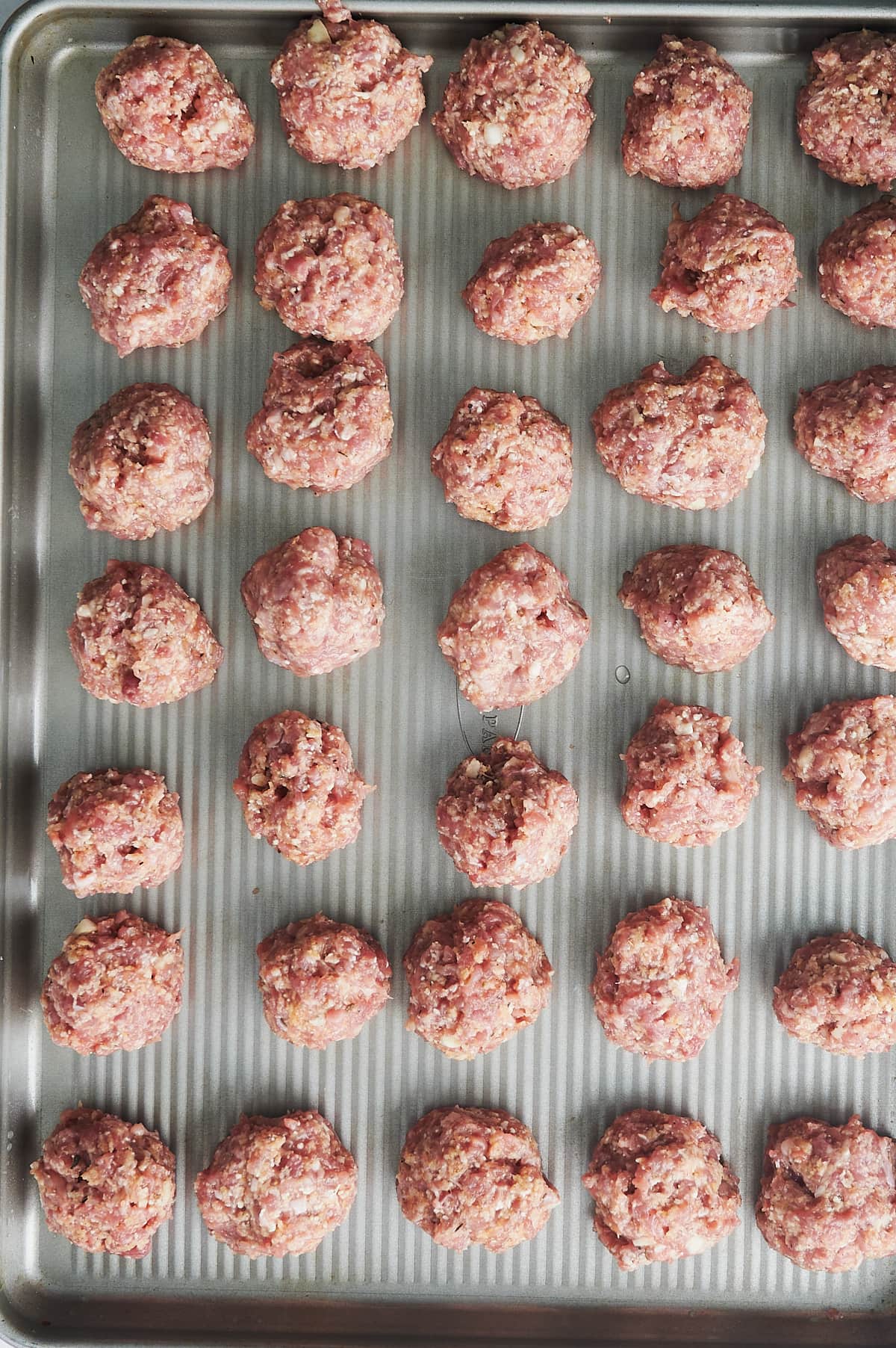 uncooked sheet pan of chicken meatballs in rows.
