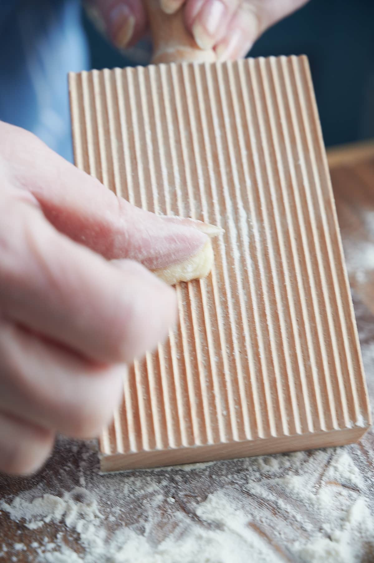 person rolling homemade cavatelli dough down ridged board